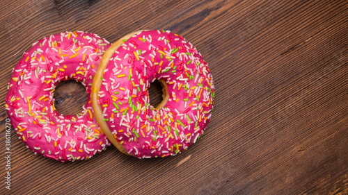 Glazed doughnuts with pink icing with sprinkles on a wooden Board,space for text