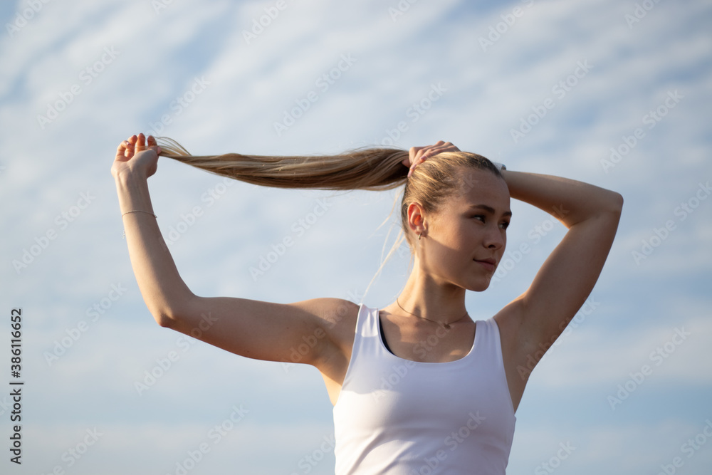young fitness portrait of woman tying ponytale young fitness portrait of woman tying ponytale