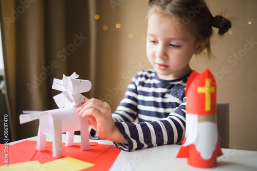 paper craft for kids. DIY toy Saint Nicholas and white horse for sinterklaas day. create art for children. girl glues horse photo