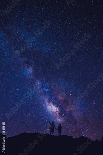 Silhouette of couple on the hill. Stargazing at Oahu island, Hawaii. Starry night sky, Milky Way galaxy astrophotography.
