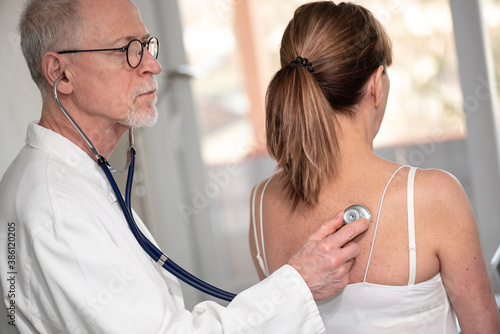 Senior doctor using stethoscope to exam patient photo