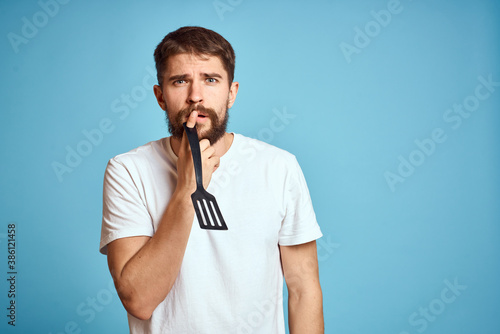 A man with a shovel for cooking in his hand on a blue background and a white T-shirt