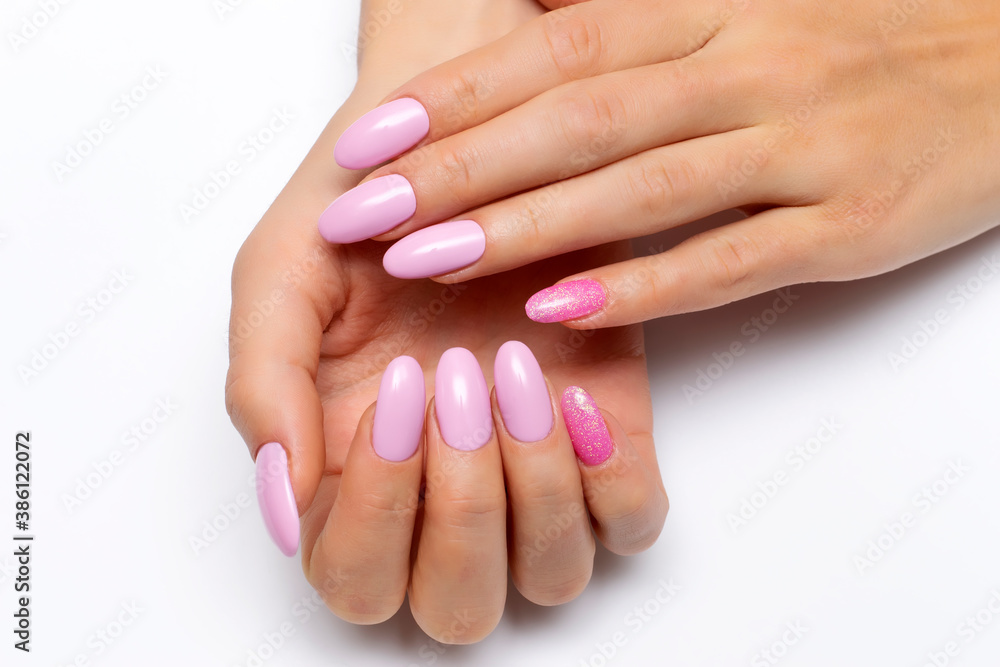Gel. Pink manicure with pink sequins on long oval nails close-up on a white background.	