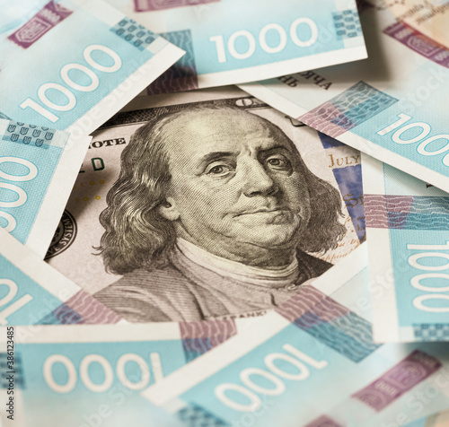 1000 Ukrainian hryvnia new banknotes of 2020 issue around the portrait of Franklin on a 100 dollar bill of America. Monetary background of several thousand hryvnia with state symbols of Ukraine. photo