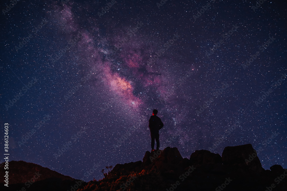 Silhouette of boy / man standing on the hill.  Stargazing at  Haleakala National Park, Maui, Hawaii. Starry night sky, Milky Way galaxy astrophotography.