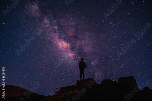  Silhouette of boy / man standing on the hill. Stargazing at Haleakala National Park, Maui, Hawaii. Starry night sky, Milky Way galaxy astrophotography.