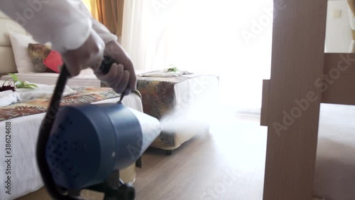 Man in white protective suit in the hotel sprays hotel rooms, elevator to prevent the contamination of corona virus.Ulv Cold Fogger machine	