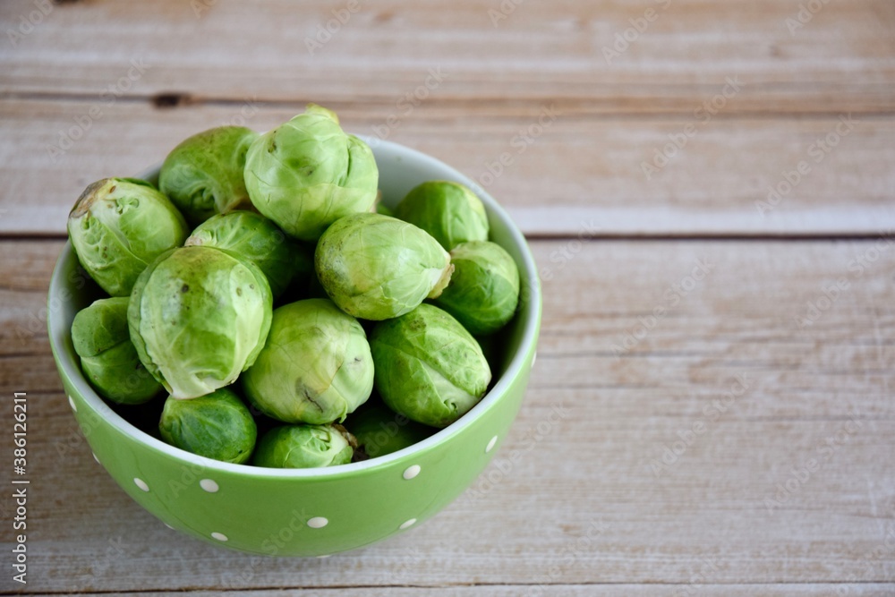 Fresh Brussel Sprouts in a bowl on wooden background Fresh Brussel Sprouts in a bowl on wooden background