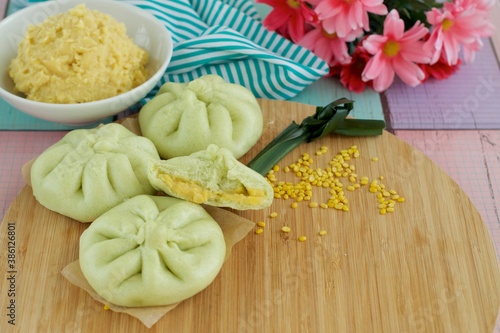 Fresh steamed Pandanus bread buns, filled with mung bean paste on wooden board