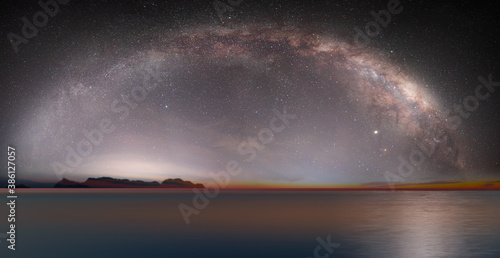 The milky way galaxy over the sea and silhouette of rock in the night sky