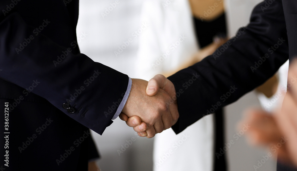 Unknown businesspeople are shaking their hands after signing a contract at meeting, close-up. Business communication concept
