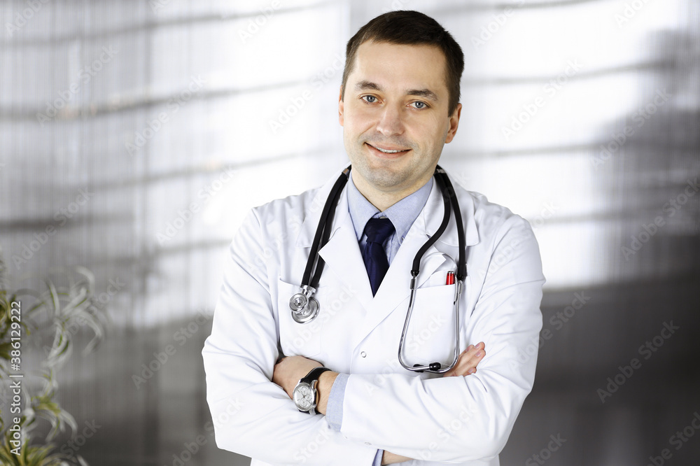 Professional doctor with a stethoscope is standing with crossed arms in a clinic. Perfect medical service in hospital. Medicine and healthcare concept Professional doctor with a stethoscope is standing with crossed arms in a clinic. Perfect medical service in hospital. Medicine and healthcare concept