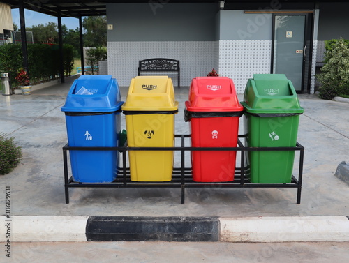 Four colored bins to separate waste types. Blue for common waste Yellow for recycling waste Red for hazardous waste and green for wet waste.