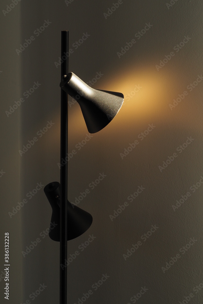 Czarna stylowa stojąca lampa na tle białej ściany. Gra światła i kolorów. - obrazy, fototapety, plakaty 