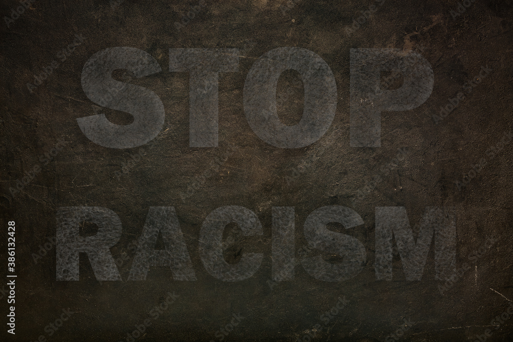 Font with transparency STOP RACISM graffiti on a black stone background. close up Font with transparency STOP RACISM graffiti on a black stone background. close up