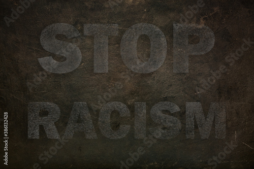 Font with transparency STOP RACISM graffiti on a black stone background. close up