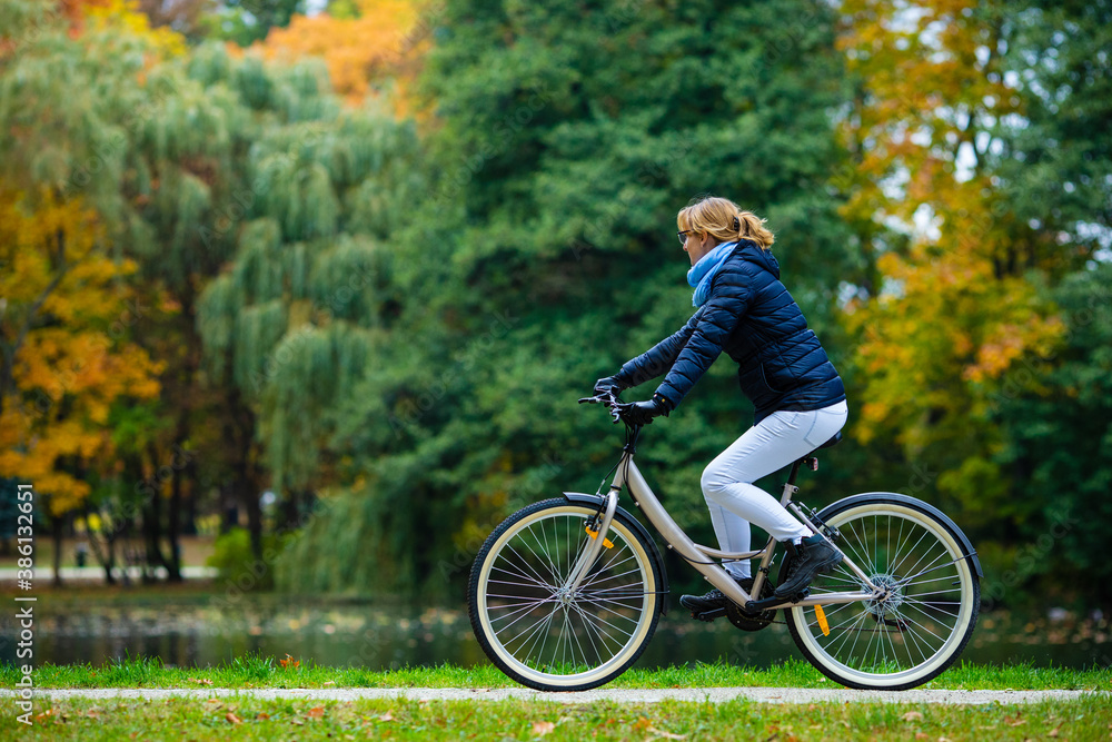 Urban biking - woman riding bicycle in city park Urban biking - woman riding bicycle in city park