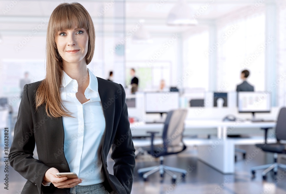 Business portrait of happy white young businesswoman with phone in office. Business portrait of happy white young businesswoman with phone in office.