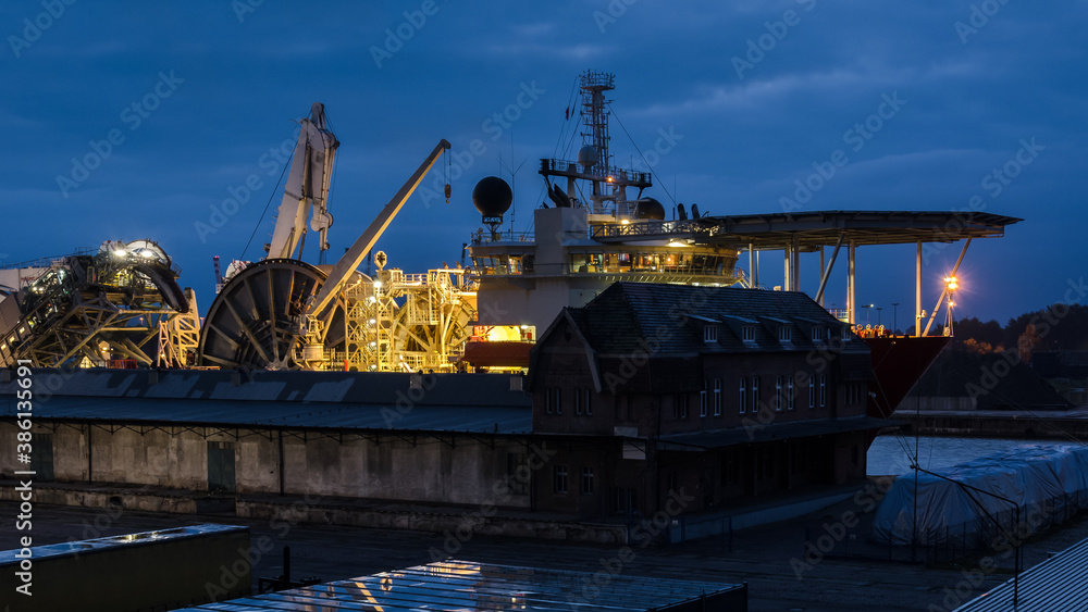 SHIP IN SEAPORT - Specialized watercraft moored at the wharf against the background of warehouse infrastructure SHIP IN SEAPORT - Specialized watercraft moored at the wharf against the background of warehouse infrastructure
