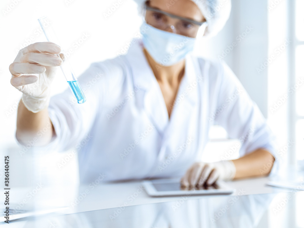 Professional female scientist in protective eyeglasses researching tube with reagents in laboratory. Concepts of medicine and science researching Professional female scientist in protective eyeglasses researching tube with reagents in laboratory. Concepts of medicine and science researching