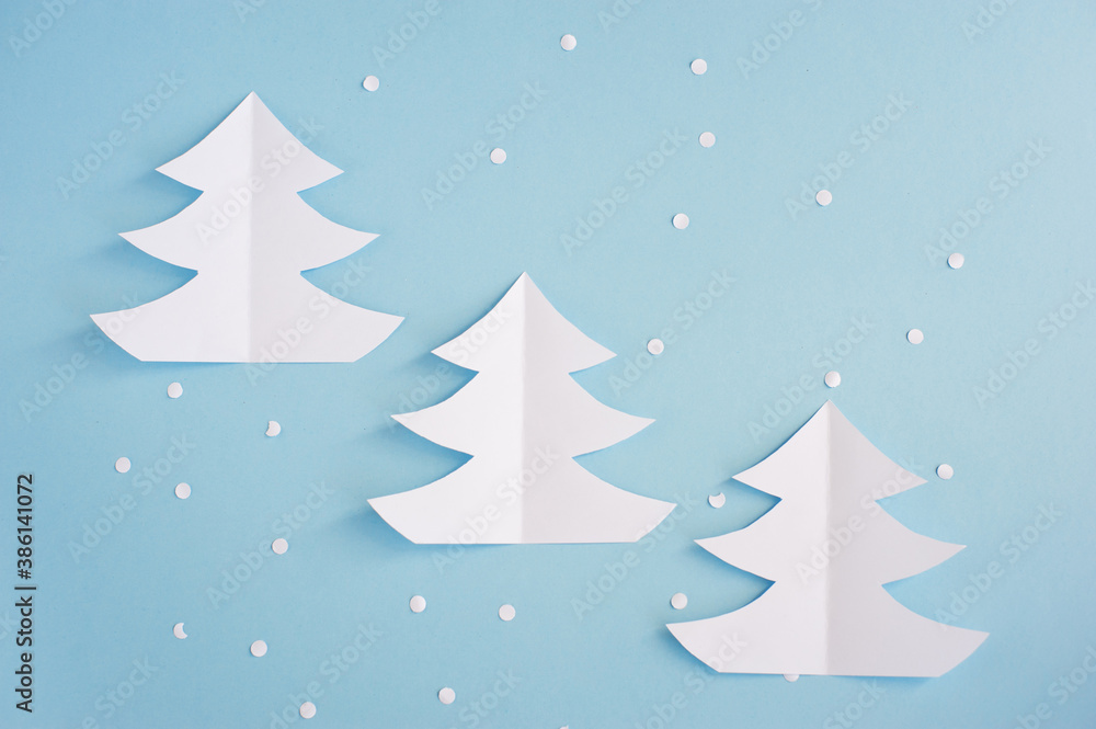 White paper Christmas trees on a blue background. Christmas decor