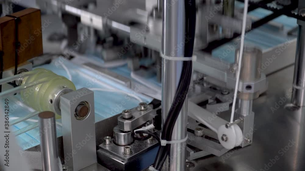 The process of manufacturing line production medical face mask with automatic machinery in an industrial factory . Shortages during the coronavirus pandemic or covid-19 outbreak The process of manufacturing line production medical face mask with automatic machinery in an industrial factory . Shortages during the coronavirus pandemic or covid-19 outbreak
