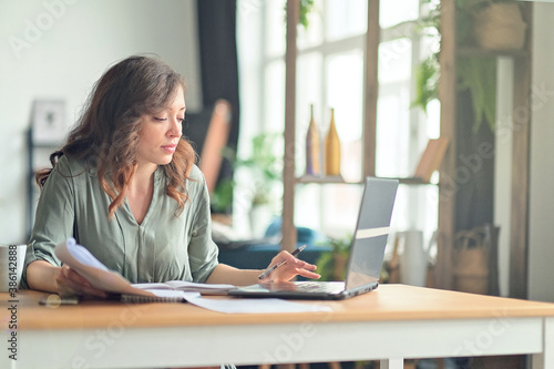 Young woman working from home office. Freelancer using laptop and the Internet. Workplace in living room.