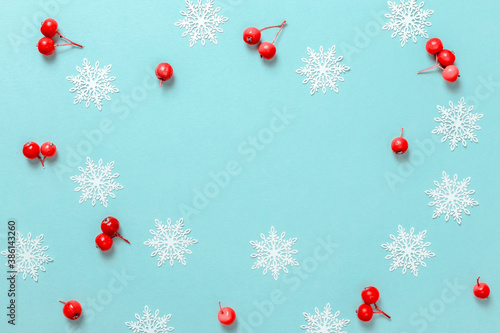 Christmas gift. White snowflakes, red berry in Christmas composition on pastel blue background for greeting card. Flat lay, top view, copy space.