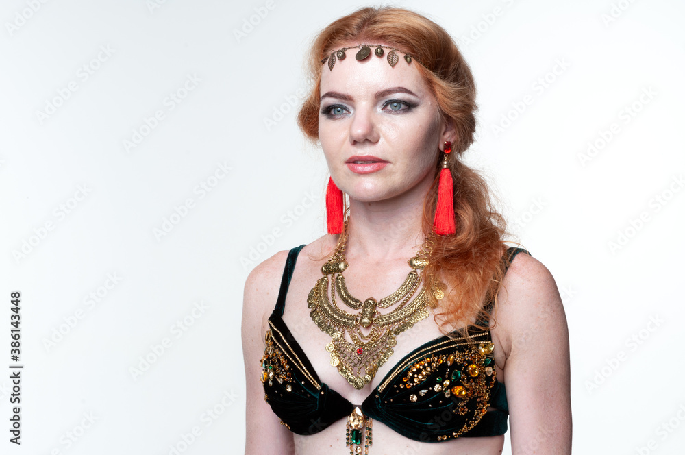portrait of beautiful woman in green belly dance costume and red earrings looking away on white background