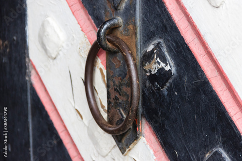 Obraz na plátně Wrought iron door handles in the form of a ring and a steel bolt closed with a padlock on the gate in a medieval castle