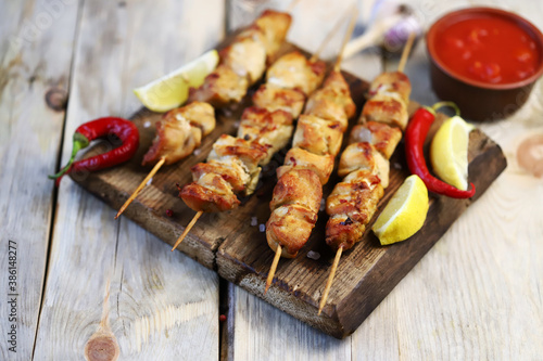 Selective focus. Appetizing chicken skewers on wooden sticks. Rustic style.