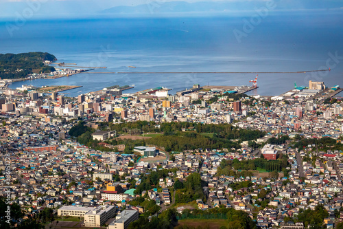 小樽山の展望台から見た、小樽の市街地とその奥にある石狩湾、雲の浮かぶ青空