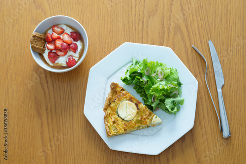 Quiche and salad on white octagonal plate, yogurt and strawberries photo