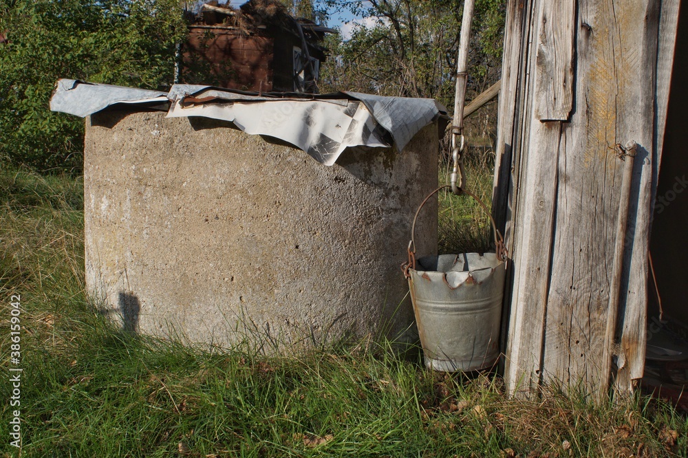 an old, unused well and a bucket hanging next to it. an old, unused well and a bucket hanging next to it.