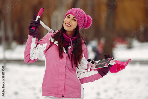 Woman in a winter park. Lady in pink sportsuit. Woman with snow scooter.