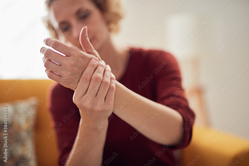 Woman with hand pain sitting on a couch at home. Woman with hand pain sitting on a couch at home.