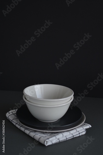 Empty black and gray monochrome plate and cup served with kitchen checkered towel. Minimalism food restaurant. Mock and copy space. Food desing.