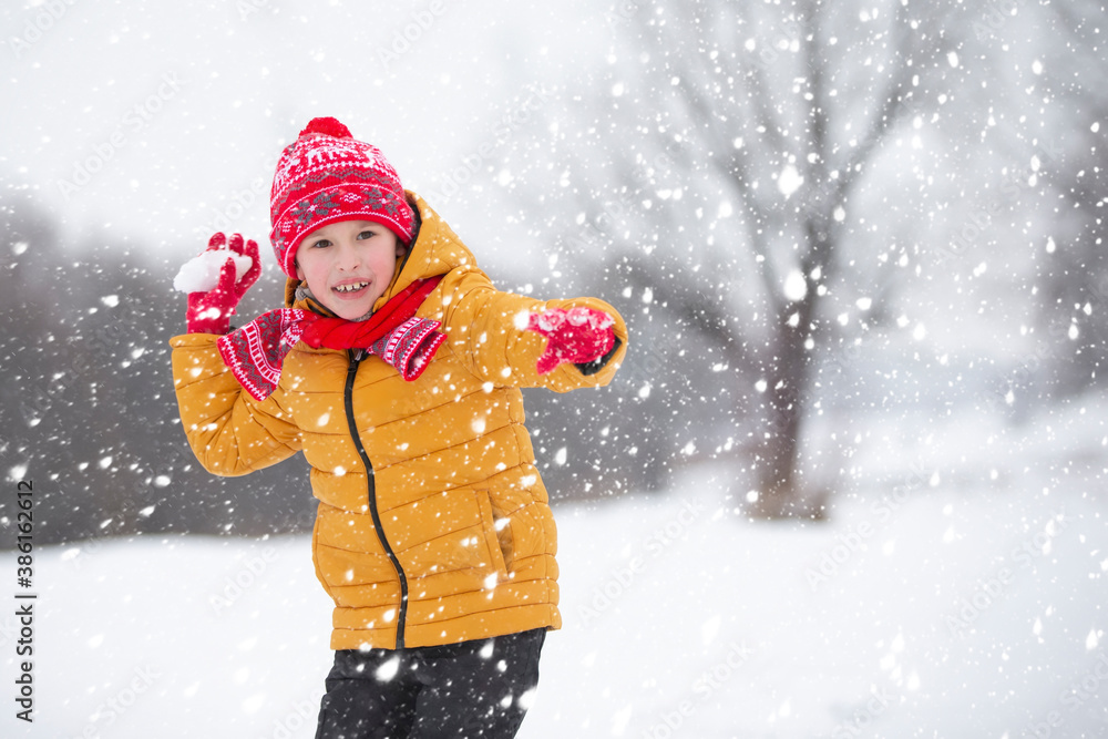 Child in winter. The boy is playing snowballs in the street. Child in winter. The boy is playing snowballs in the street.