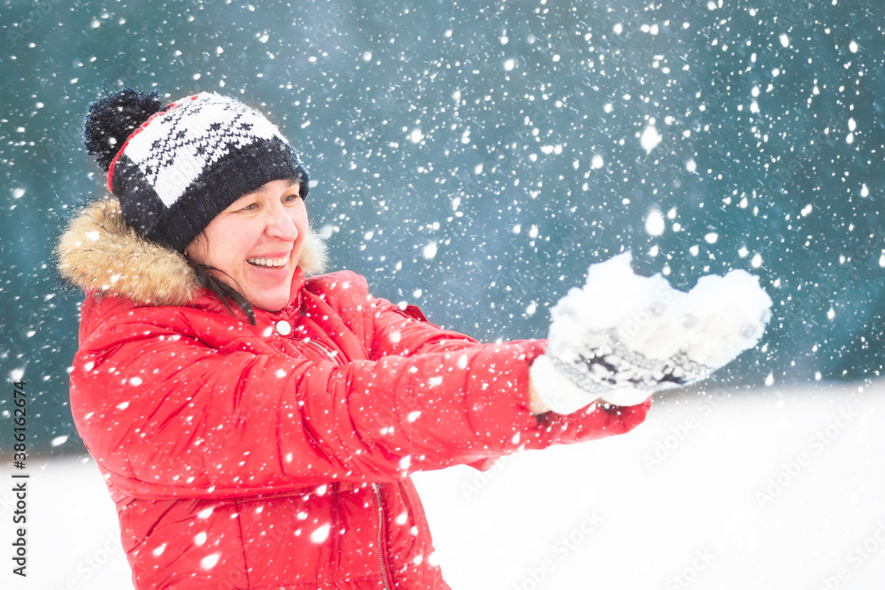 Adult woman in bright clothes holds snow. People in snowy winter. Adult woman in bright clothes holds snow. People in snowy winter.