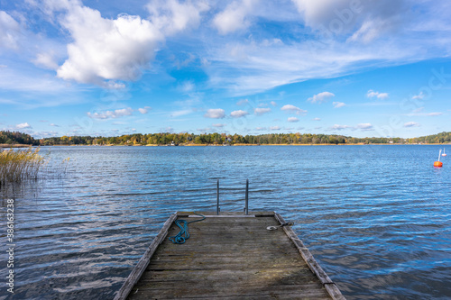 Old wooden pier or jetty for yachts and boats. Autumn landscape of the coast of Sweden. Forest islands with colorful trees in the gulf of the Baltic Sea. Panoramic view of Scandinavia in an autumn.