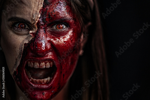 Zombie makeup on Halloween 2020. Creative art make-up for eve of All Saints Day party. Creepy bloody face. Close-up portrait of horrible woman. Horror.