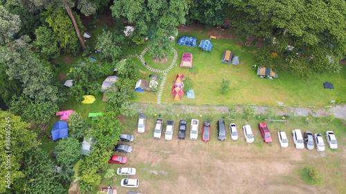 Top View of Multi-colored tents in the garden with green plants, and car park.