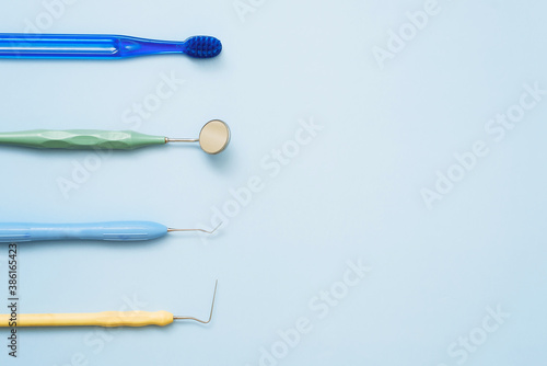 Toothbrush and mirror, tweezers and probe for dental treatment on a blue background. Flat lay, copyspace