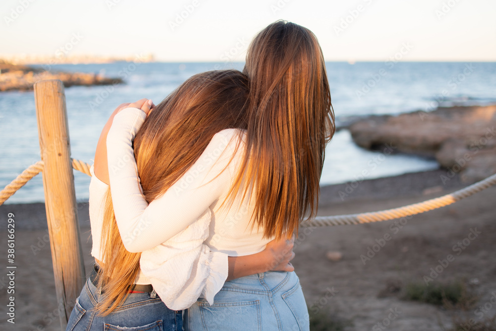 Two young girls embracing each other at the beach