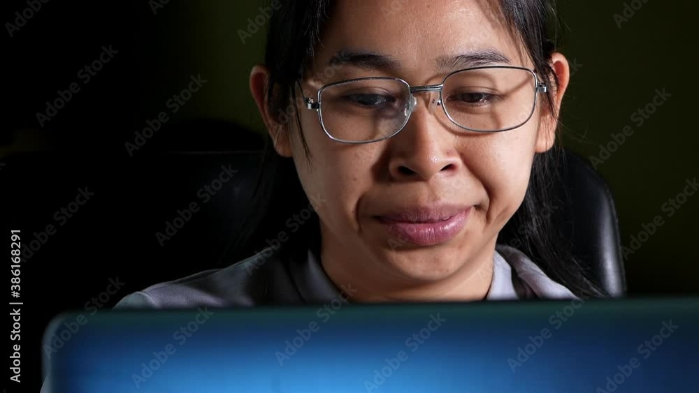 Tired woman wearing glasses using laptop computer technology while sitting on table at night. Young woman yawns sleepy due to hard work overtime at home. work at home concept. Tired woman wearing glasses using laptop computer technology while sitting on table at night. Young woman yawns sleepy due to hard work overtime at home. work at home concept.