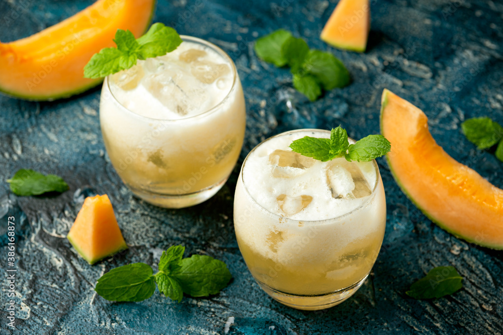 Refreshing Cantaloupe Melon cocktail with ice and mint on rustic table Refreshing Cantaloupe Melon cocktail with ice and mint on rustic table