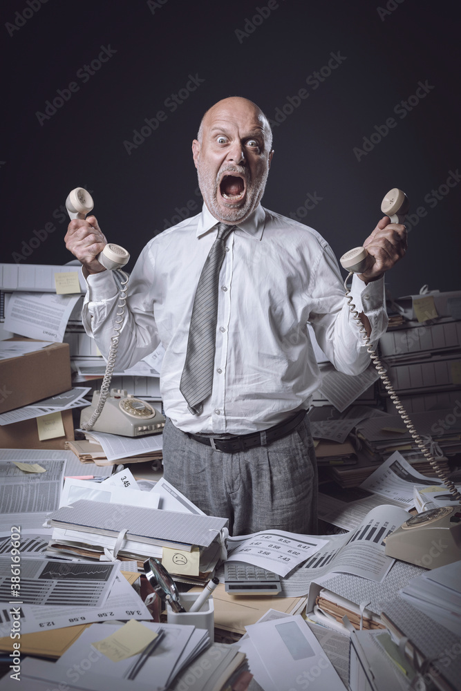 © stokkete - Stressed businessman working in a messy office