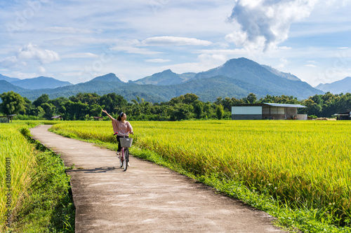 Young happy woman enjoying and riding a bicycle in paddy field while traveling at Pua, Thailand