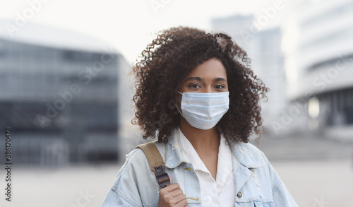 Young woman wearing protective face mask in a city, Masked african teenage student girl on a city street,  Epidemic, pandemic, corona virus protection, healthy lifestyle, people concept photo