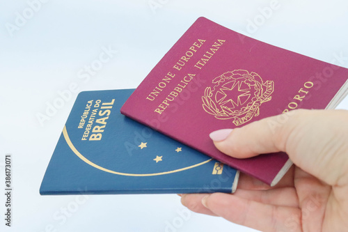 woman hand holding italian and brazilian passport - showing or delivering- dual citizenship concept photo